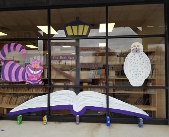 A peek at The Book Haus's new location. The window features paintings of the Cheshire Cat, a lamp post, an open book, and Harry Potter's Hedwig.
