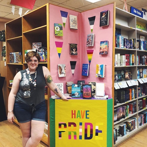 A bookseller posing with a Pride-themed display.