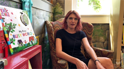 Janet Geddis of Avid Bookshop sitting in armchair next to children's book shelf