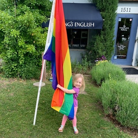 A little girl at The King's English Bookshop posing with a Pride flag.