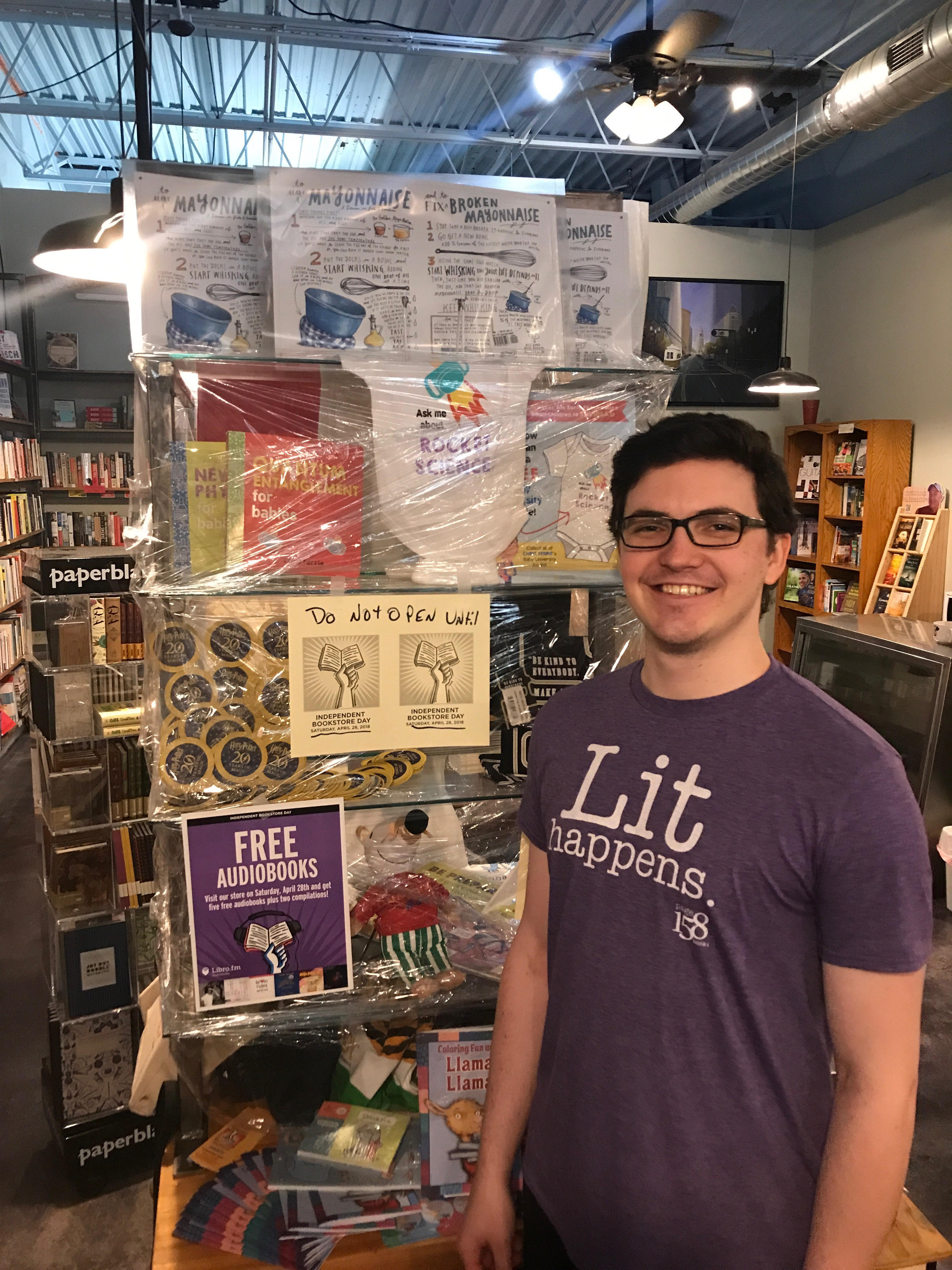 Bookseller Josh Lucey shows off a case of shrink-wrapped IBD merchandise at Page 158 Books.